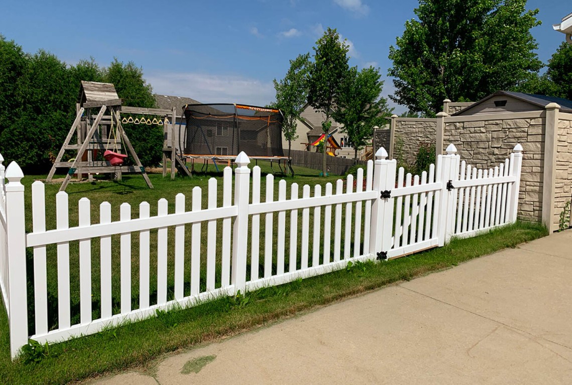 Low-maintenance white vinyl picket fence installation around residential yard